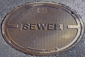 Metall-Schachdeckel auf der Straße mit dem Wort "Kanal" geprägt