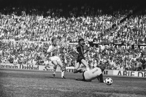 Schwarzes und wei├čes Foto von Fü├čballspielern in Aktion auf einem Feld mit Zuschauern im Hintergrund und einer Bundesliga 1978-79 Ajax 1-1 Hannover 96-Tafel.