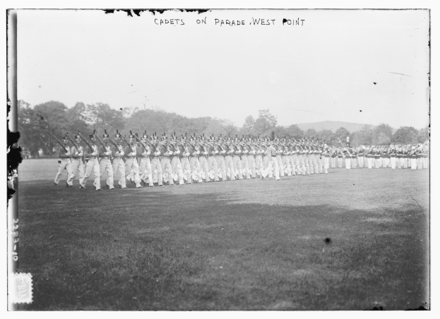 Gruppe von Menschen, einige mit Gewehren, auf dem Boden stehend mit Bäumen, Hügeln und einem bewölkten Himmel im Hintergrund, mit dem Text "cadets on parade west point" oben.
