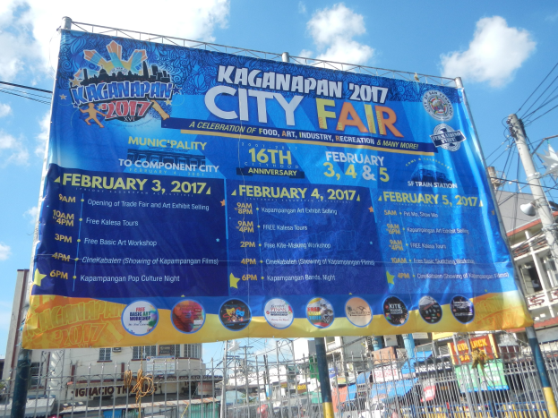 Plakat mit der Aufschrift 'Kaganapan City Fair 2017' umgeben von Infrastruktur und klarem Himmel.