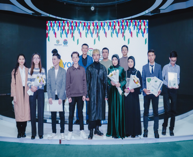 Gruppe von Menschen auf einer Bühne mit Blumensträußen und Urkunden, vor dem Hintergrund "Jugend-Solar-Awards 2019"
