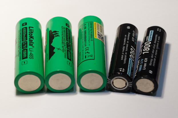 Vier grüne Li-ion wiederaufladbare 18650-Batterien, die als "Li-ion" und "18650" beschriftet sind und nebeneinander auf einer weißen Oberfläche placed.