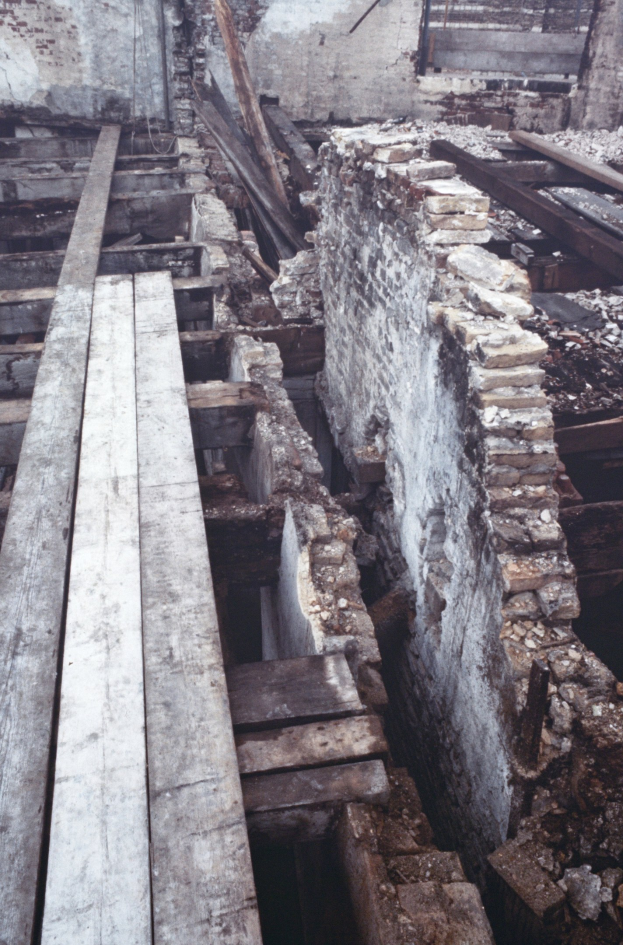 Altbau im Abriss mit verstreuten Holzplanken und Steinen und einer sichtbaren Wand im Hintergrund.