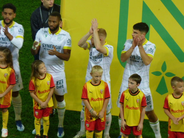 Eine Gruppe von Fußballspielern in Uniform klatscht auf einem Ligue-1-Feld in celebration