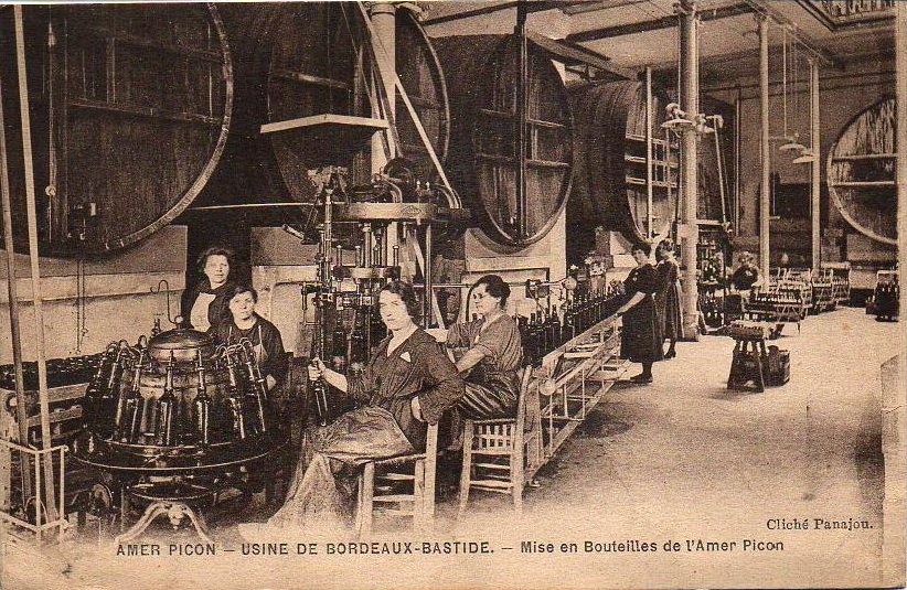 Schwarzes und weißes Foto von Frauen bei der Arbeit in einer Fabrik, sitzend und stehend mit Maschinen und Gegenständen, mit Text "Amer Picon - Use de Bordeaux-Bastide" unten.