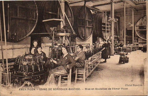 Schwarzes und weißes Foto von Frauen bei der Arbeit in einer Fabrik, sitzend und stehend mit Maschinen und Gegenständen, mit Text "Amer Picon - Use de Bordeaux-Bastide" unten.
