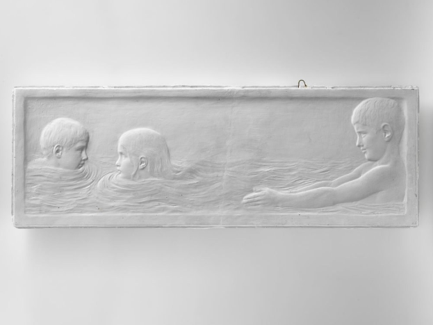 Drei Kinder beim Schwimmen in einem Pool mit einer Wand im Hintergrund.