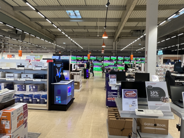 Großer Raum in einem Walmart-Laden voller Elektronik, die in Regalen angeordnet ist, Deckenleuchten, Ventilatoren, Schilder und Menschen auf dem Boden.