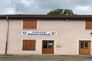 Gebäude der Polizei municipaux mit einem Schild, Fenstern, Türen, einer Namensschild, einem Rohr, einem Baum und einem bewölkten Himmel im Hintergrund.