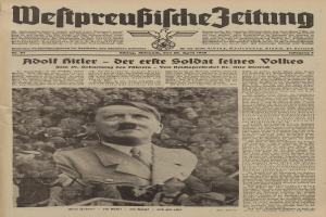 Adolf Hitler, gekleidet in einem schwarzen Anzug und weißem Hemd, steht vor einer Menge auf der Titelseite einer deutschen Zeitung mit der Überschrift "Adolf Hitler - Der Erte Soldat Feines Volkes".