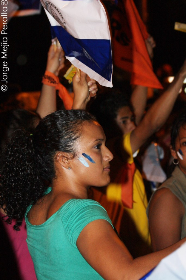 Frauen in grünen T-Shirts bei einer Demonstration, die weiße Tücher halten, mit anderen Mädchen im Hintergrund.