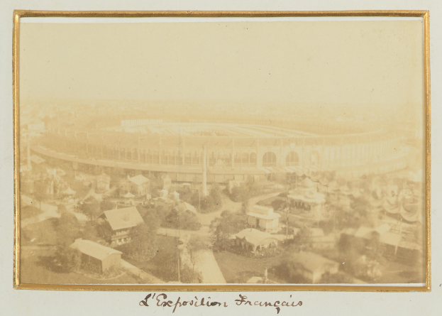 Altes Schwarz-Weiß-Foto eines Stadions, umgeben von mehrstöckigen Gebäuden, Bäumen und Strommasten, mit Text am unteren Rand.
