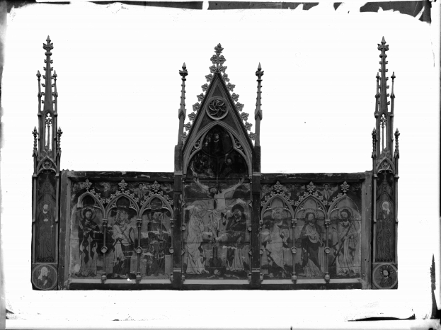 Schwarzes und weißes Foto einer gotischen Kirche mit detaillierten Wandverzierungen, einem Turm und einem großen Fenster mit detaillierten religiösen Symbolen und Figuren.