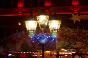 Eine Straßenlaterne mit dekorativen Lichtern und Schmuck steht in einer Stadt in der Nacht, mit einem Gebäude im Hintergrund.