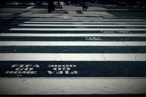 Einige Menschen überqueren eine Zebrastreifenfurt mit mehreren Autos in der oberen linken Ecke.