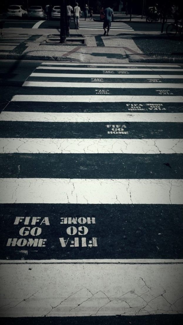 Einige Menschen überqueren eine Zebrastreifenfurt mit mehreren Autos in der oberen linken Ecke.