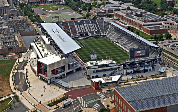 Luftaufnahme des Audi Field, des Heimstadions von Atlanta United Football Club, umgeben von Stadtgebäuden, Bäumen, Straßen, Fahrzeugen und Gras.