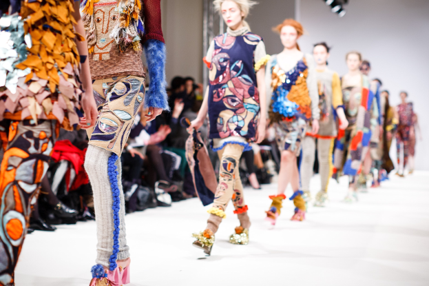 Eine Gruppe Von Frauen, Die Eine Laufsteg In London Fashion Week Heruntergehen, Mit Sitzenden Zuschauern Und Heller Beleuchtung Im Hintergrund, Erzeugt Ein Etwas Verwischtes, Traumhaftes Effekt.