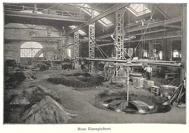 Schwarzes und weißes Foto eines Fabrikinneren mit Arbeitern, die Maschinen bedienen, umgeben von Metallstangen und -pfählen, beschriftet mit "Neue Eisengießerei, die erste Fabrik in Deutschland" unten.