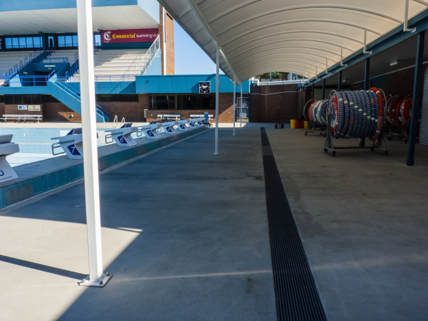 Große Hallenbad mit zahlreichen Stühlen, Polen und einem Gebäude im Hintergrund an der Universität von Texas in Austin.