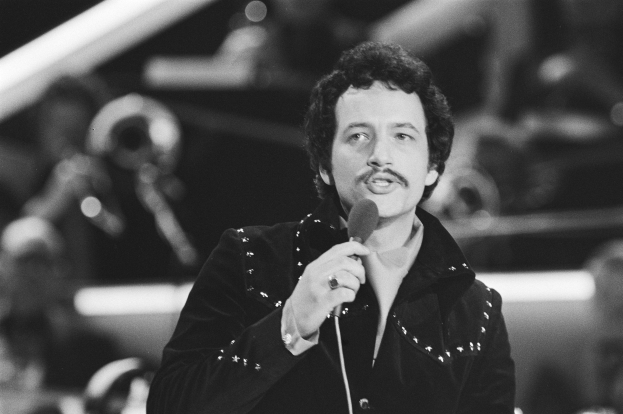 Schwarzes und weißes Foto von Elvis Presley, der ein Mikrofon hält.