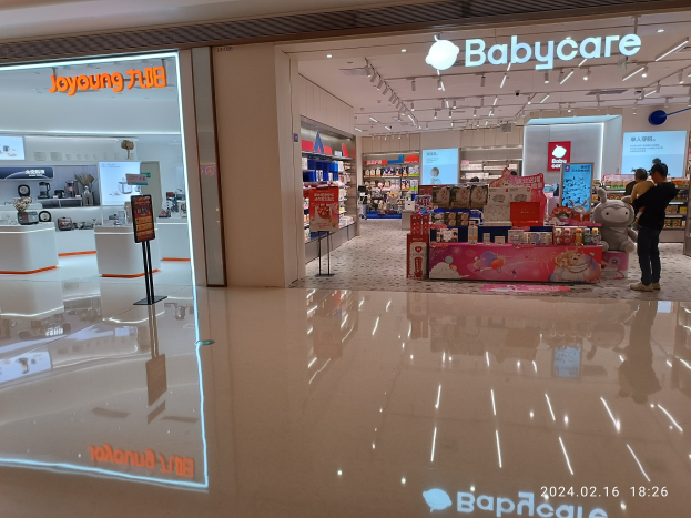 Ein Babyladen in einem Einkaufszentrum mit Menschen, Spielzeugen, Regalen, Schildern, einem Anzeigebildschirm und Deckenleuchten, das sich im Mall of Asia befindet.