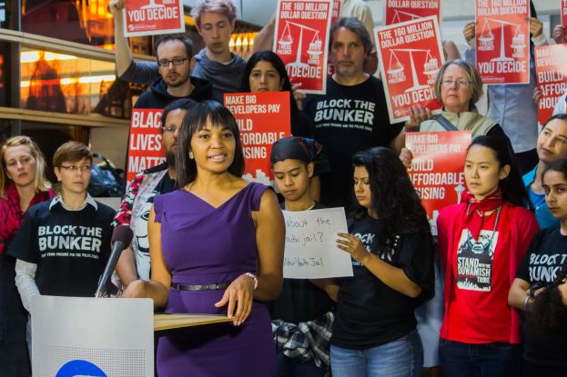 Eine Black-Lives-Matter-Aktivistin spricht in ein Mikrofon vor einer Menge mit Schildern.