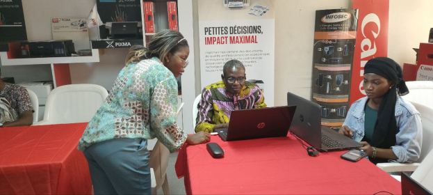 Eine Gruppe von Menschen sitzt an einem Tisch mit Laptops und Mobiltelefonen auf einer internationalen Geschäftsmesse in Senegal.