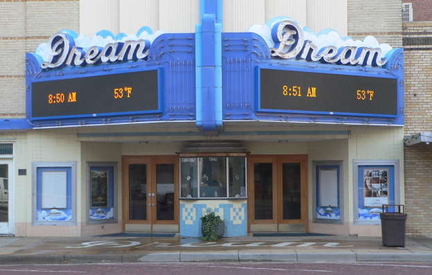 Außenansicht des Dream Theaters in St. Louis, Missouri, mit Glasfenstern und -türen, einem Namensschild, einem Müllbehälter, einer Topfpflanze und einer Straße unten.